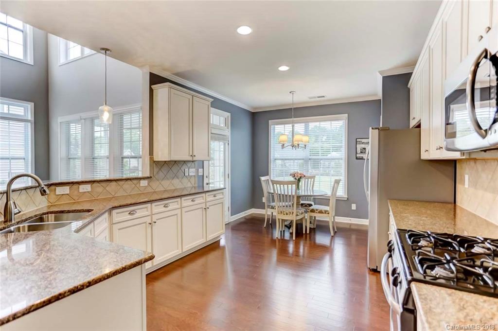 516 Rosemary Lane Fort Mill, SC 29708 - Photo 8 of 36 a kitchen with stainless steel appliances granite countertop a stove top oven a sink a dining table and chairs with wooden floor