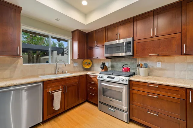 a kitchen with stainless steel appliances granite countertop wooden cabinets a sink and a stove