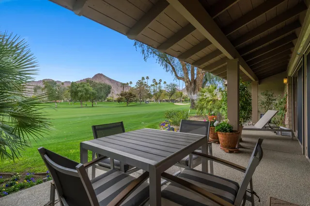 a view of a wooden chairs and table in patio with a backyard