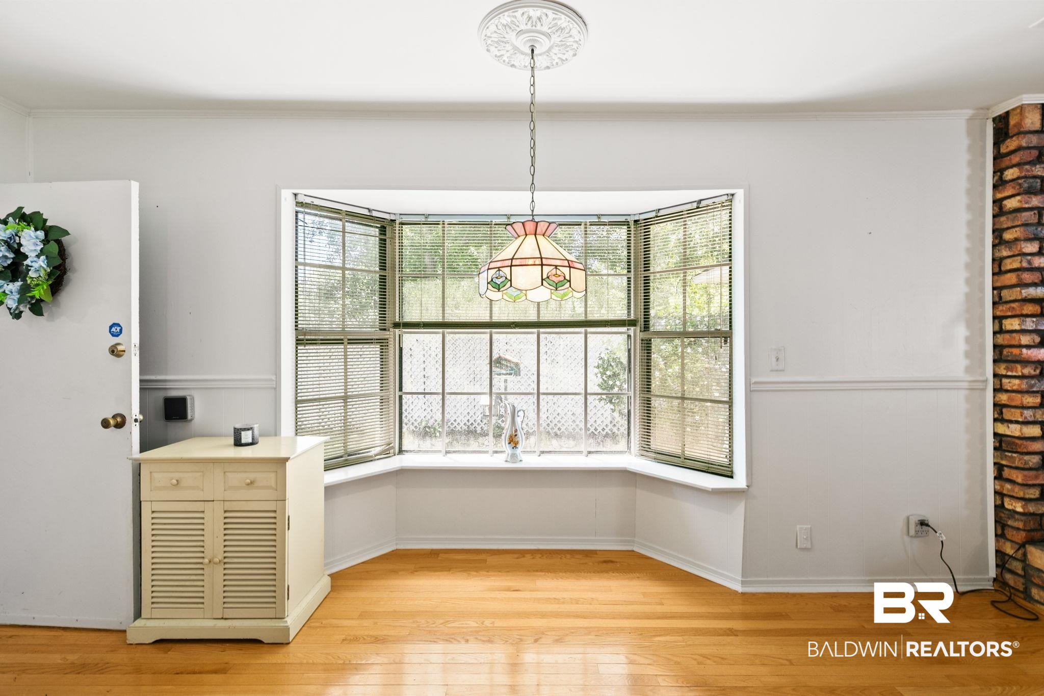 927 Cleveland Road Saraland, AL 36571 - Photo 33 of 80 Bay window with gridded panes, hardwood flooring, brick-clad architectural element, white painted walls, and a decorative ceiling medallion