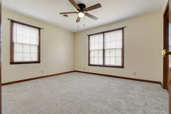 an empty room with windows and ceiling fan