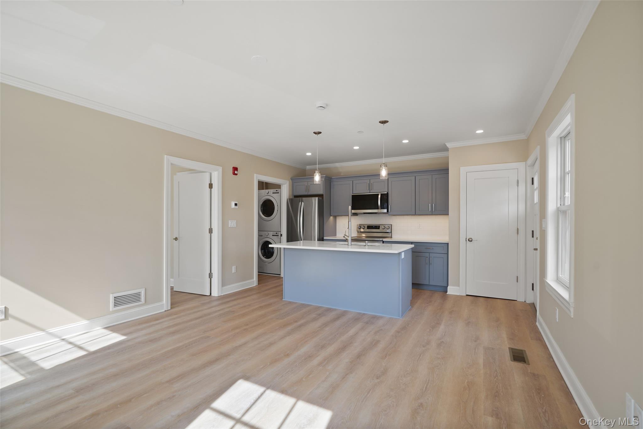5 Edgemont Road, Unit 1 Katonah, NY 10536 - Photo 3 of 6 Kitchen with stainless steel appliances, gray cabinets, stacked washer and dryer