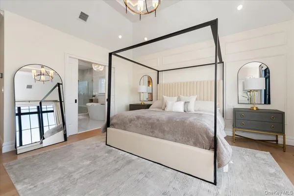 a bedroom with a bed a mirror and windows