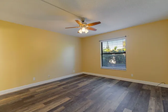 a view of an empty room with a window and wooden floor