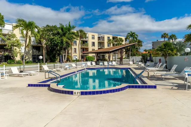 a view of swimming pool with outdoor seating and trees in the background