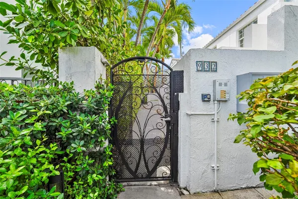 a palm plant sitting in front of a house with wooden fence