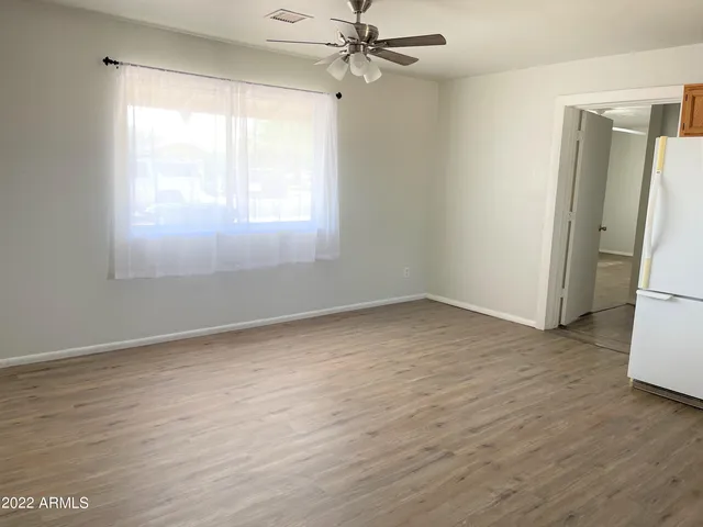 an empty room with a window and a refrigerator