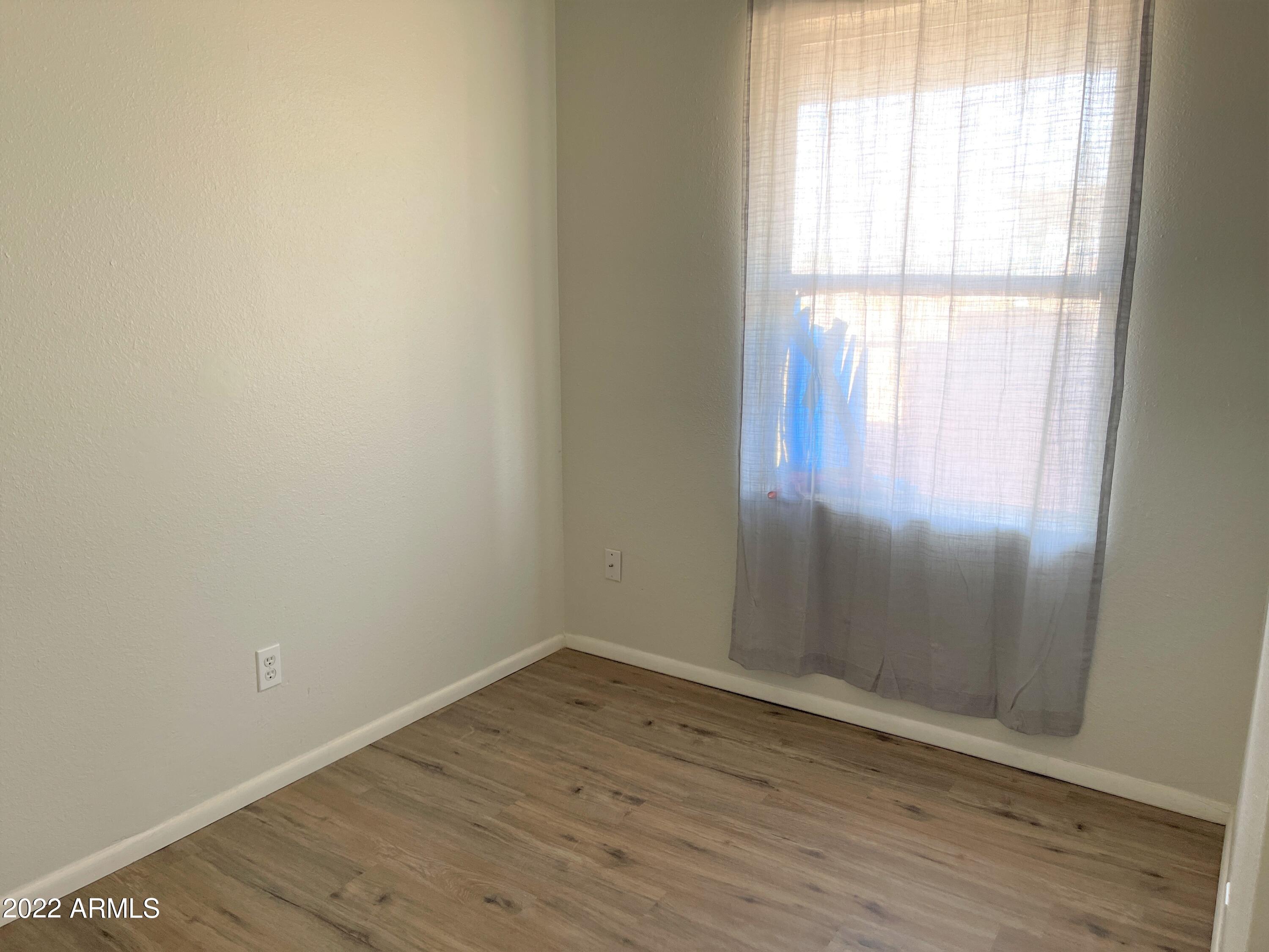 1504 North French Street, Unit B Casa Grande, AZ 85122 - Photo 19 of 23 an empty room with wooden floor and windows