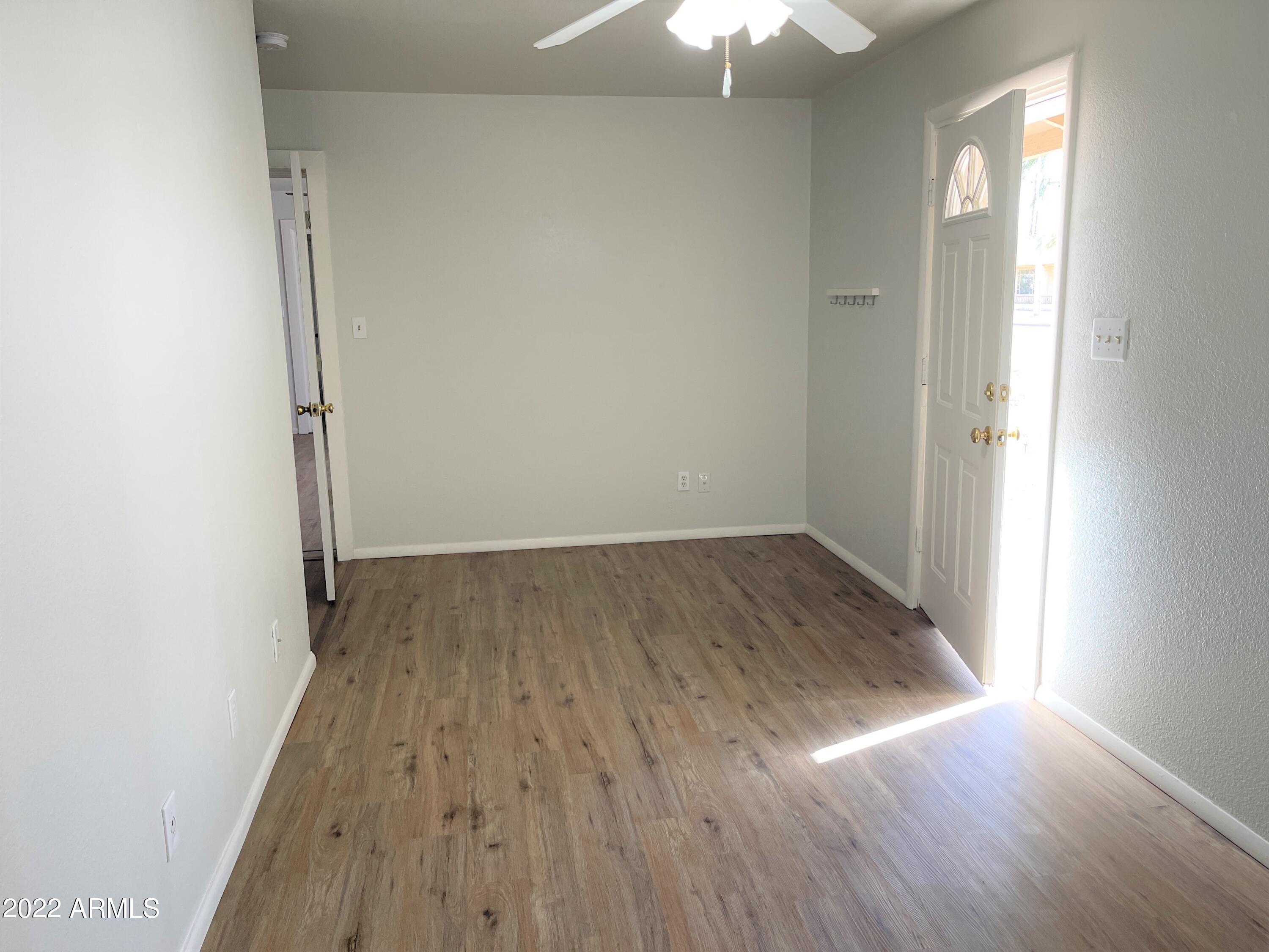1504 North French Street, Unit B Casa Grande, AZ 85122 - Photo 4 of 23 an empty room with wooden floor chandelier fan and windows
