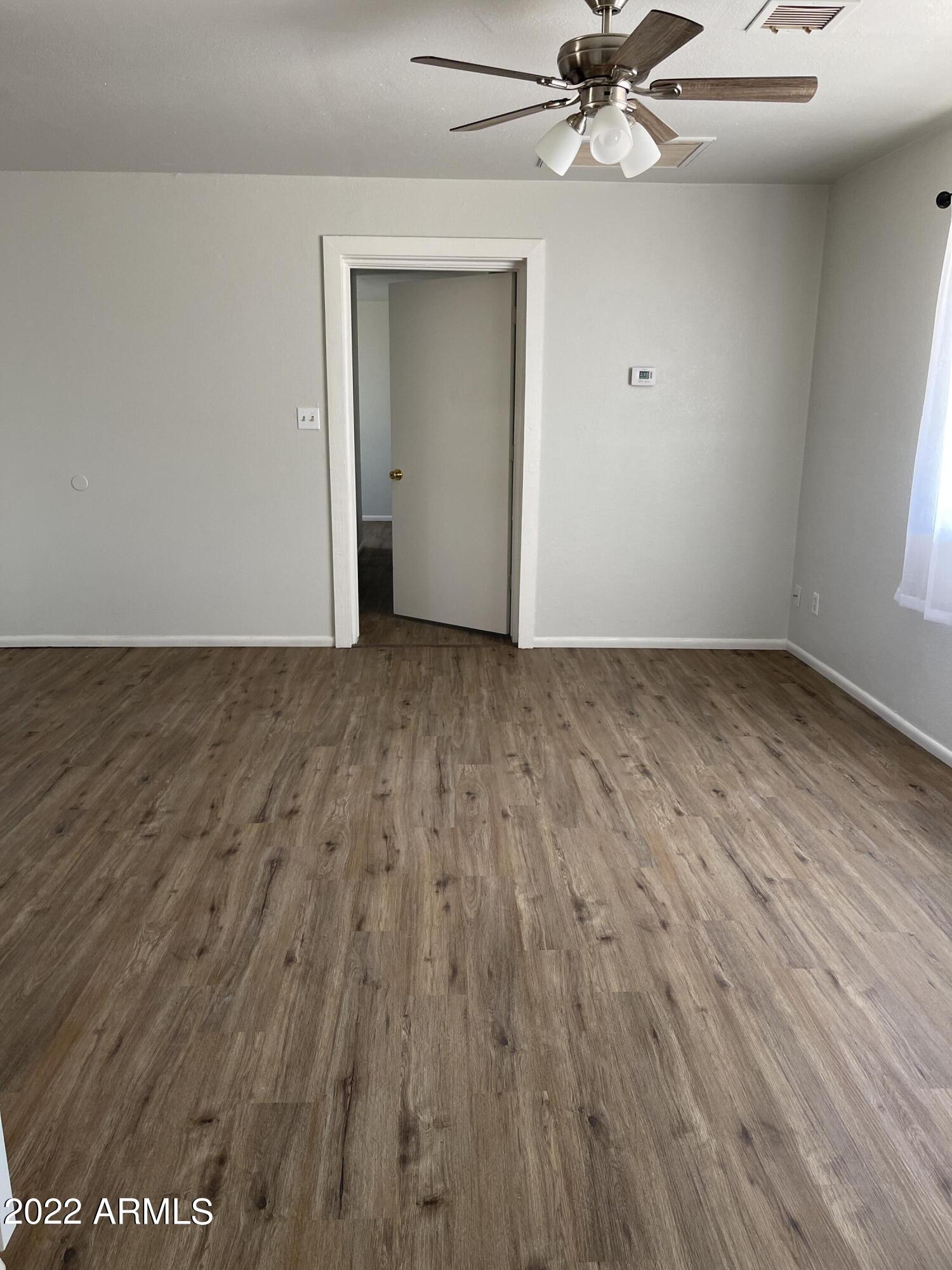 1504 North French Street, Unit B Casa Grande, AZ 85122 - Photo 5 of 23 a view of an empty room with wooden floor and a ceiling fan