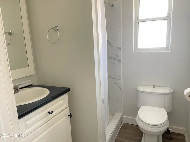 a bathroom with a granite countertop toilet a sink and a mirror