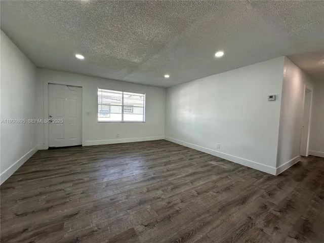 an empty room with wooden floor and window