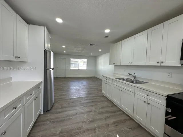 a kitchen with kitchen island white cabinets appliances and a sink