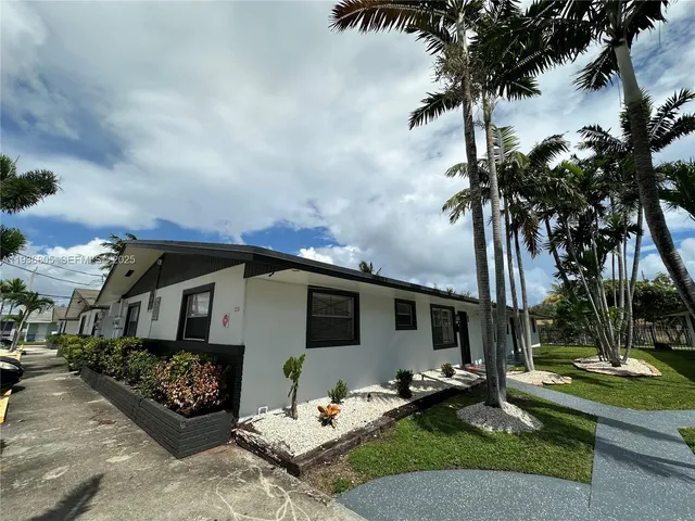 a front view of a house with garden and trees