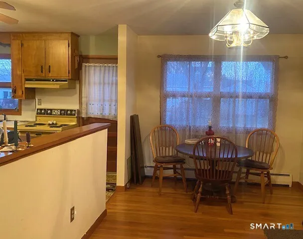 a kitchen with stainless steel appliances granite countertop a stove a sink refrigerator and a dining table with wooden floor