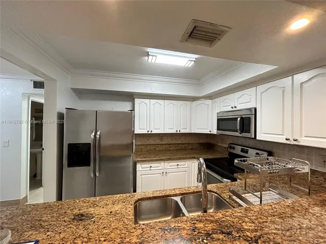 a kitchen with granite countertop a refrigerator and a sink