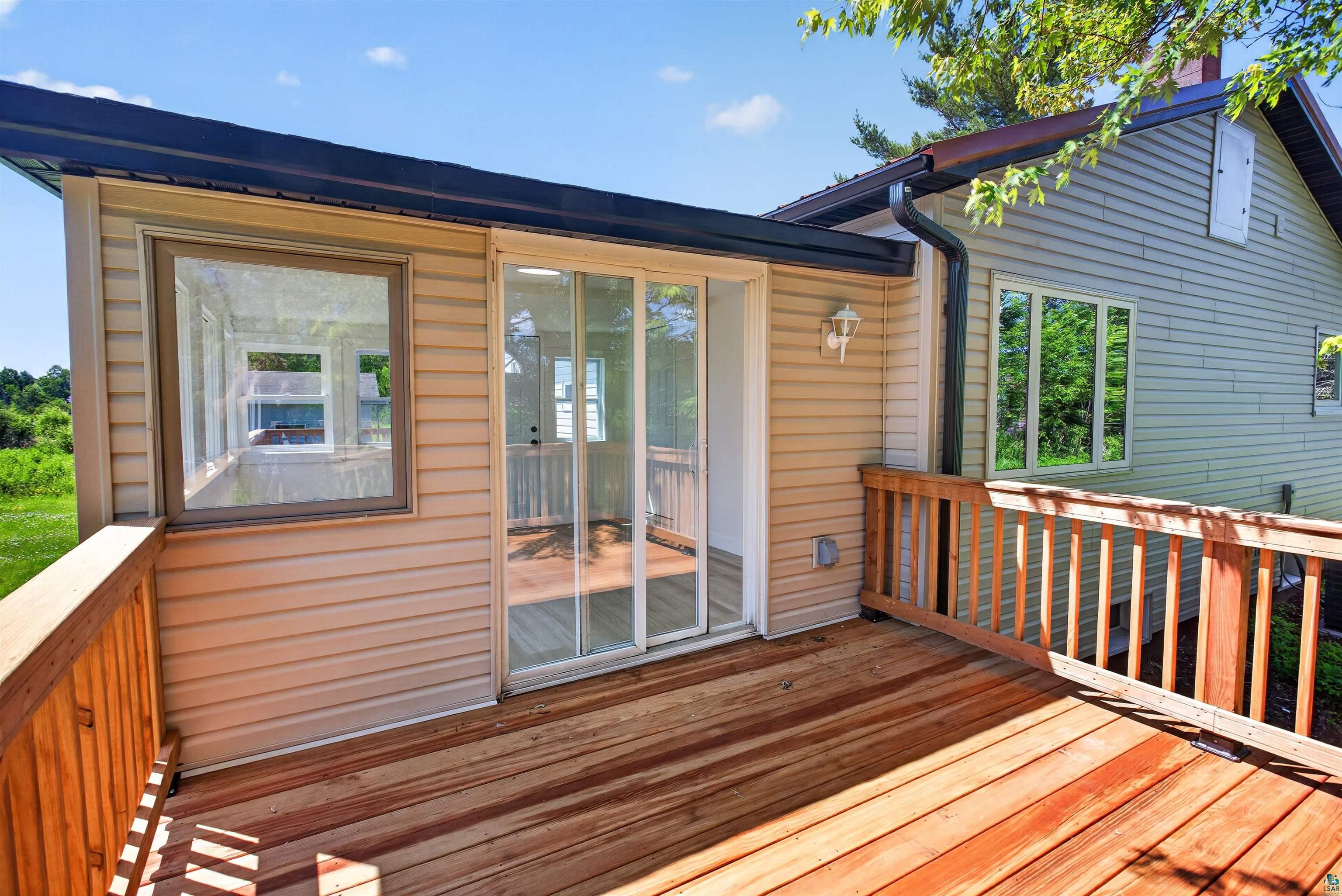 5868 Rice Lake Road Duluth, MN 55803 - Photo 21 of 39 Expansive wood-finish deck with wood railings, sliding glass door access, and an exterior light fixture