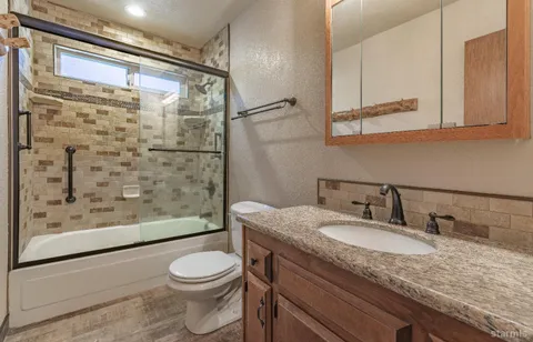 a bathroom with a granite countertop sink toilet and shower