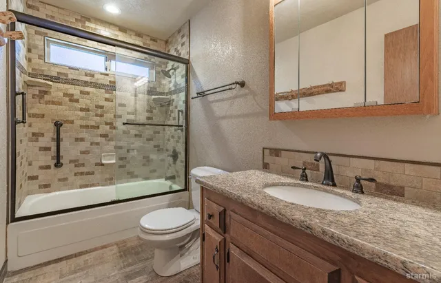 a bathroom with a granite countertop sink toilet and shower