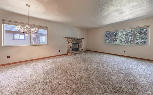 a view of an empty room with chandelier and window
