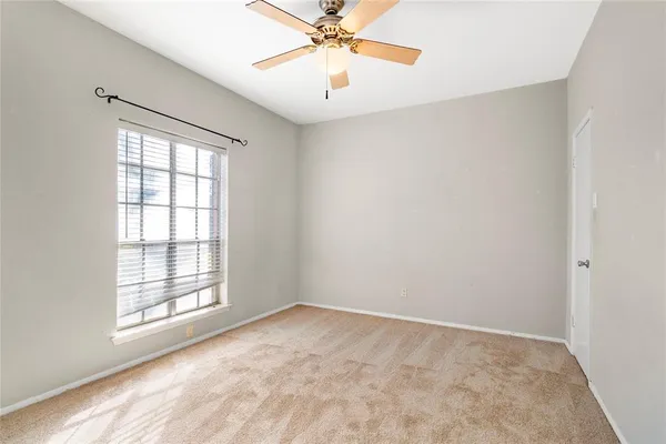 an empty room with a window and a fan