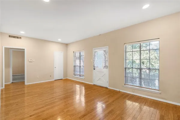 a view of an empty room with wooden floor and a window