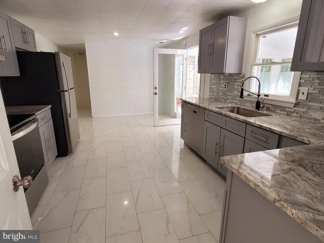 a large kitchen with stainless steel appliances a sink a stove a refrigerator a window and a counter top space