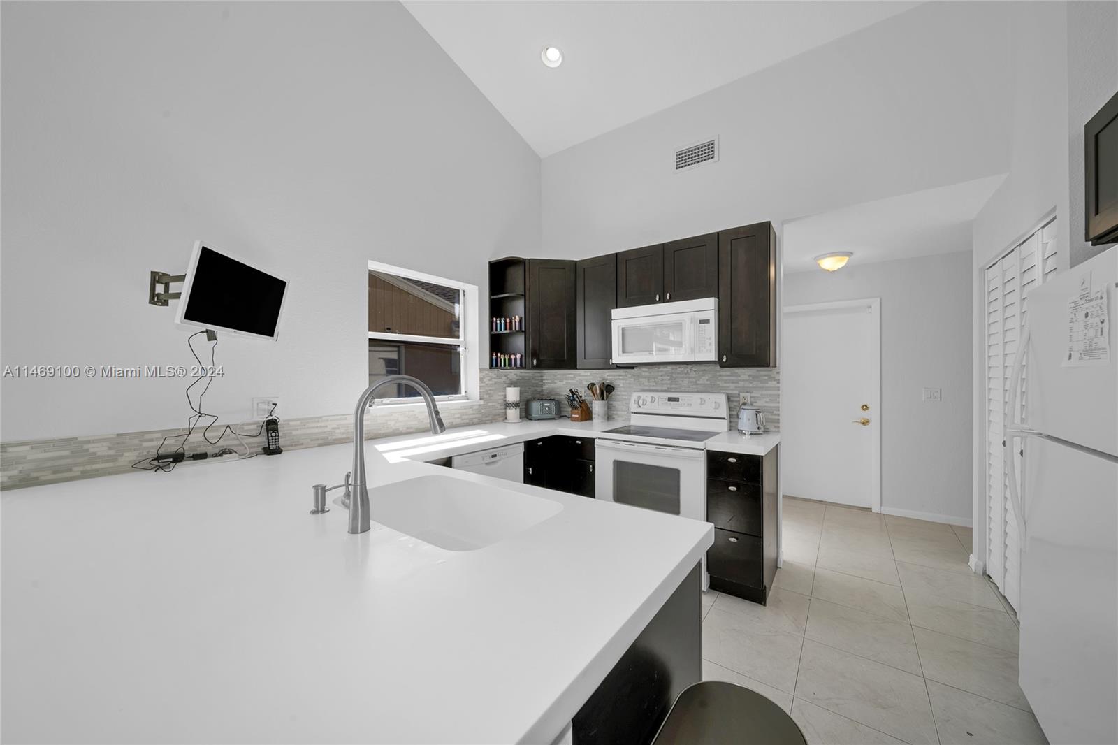 12083 Rockwell Way Boca Raton, FL 33428 - Photo 9 of 47 a white kitchen with a stove and a flat screen tv