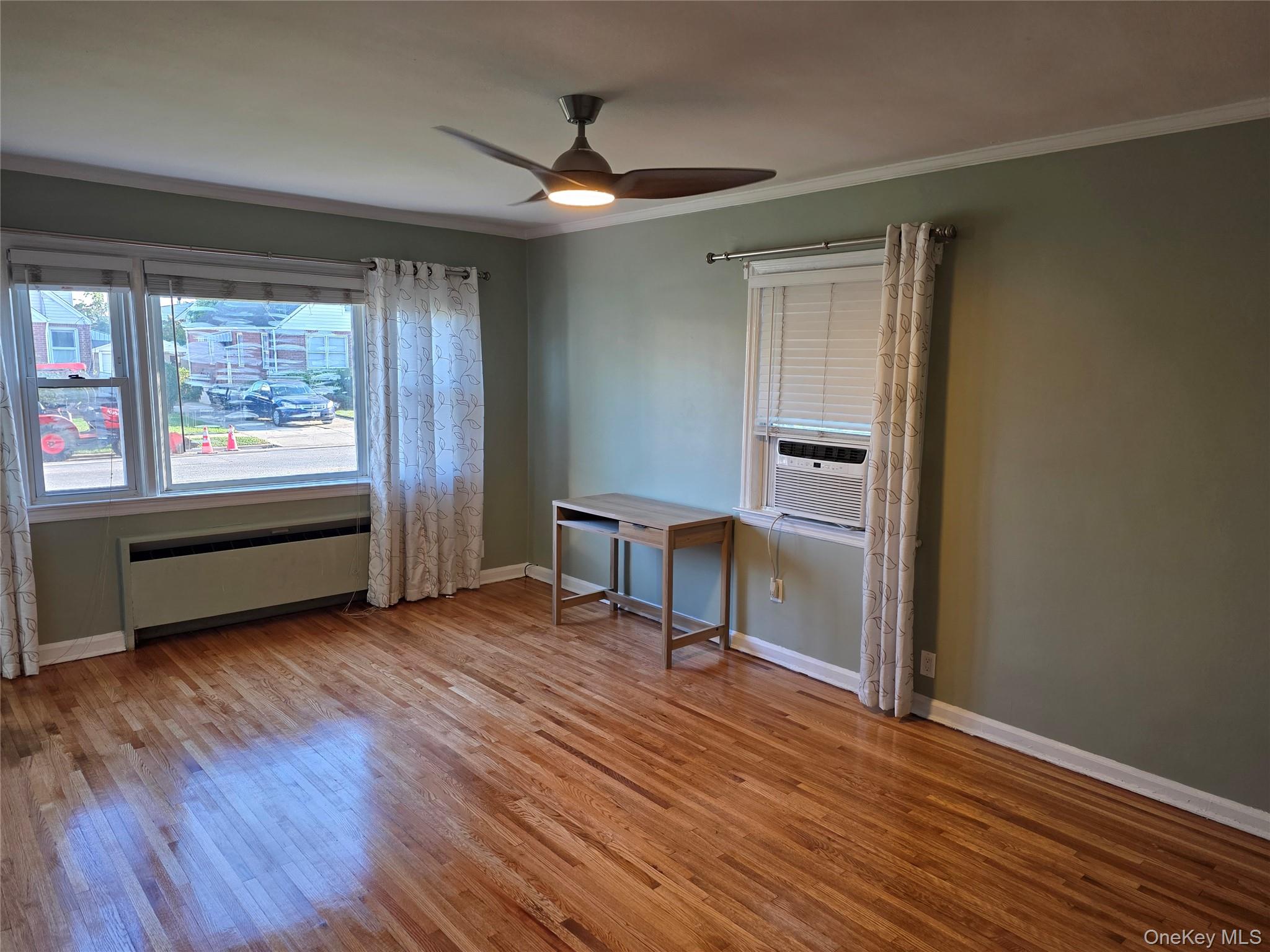 220 Raff Avenue Mineola, NY 11501 - Photo 9 of 22 Huge living room featuring ornamental molding, light wood-style floors, a ceiling fan, radiator, and cooling unit