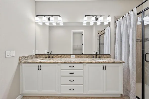a bathroom with a granite countertop sink toilet mirror and bathtub