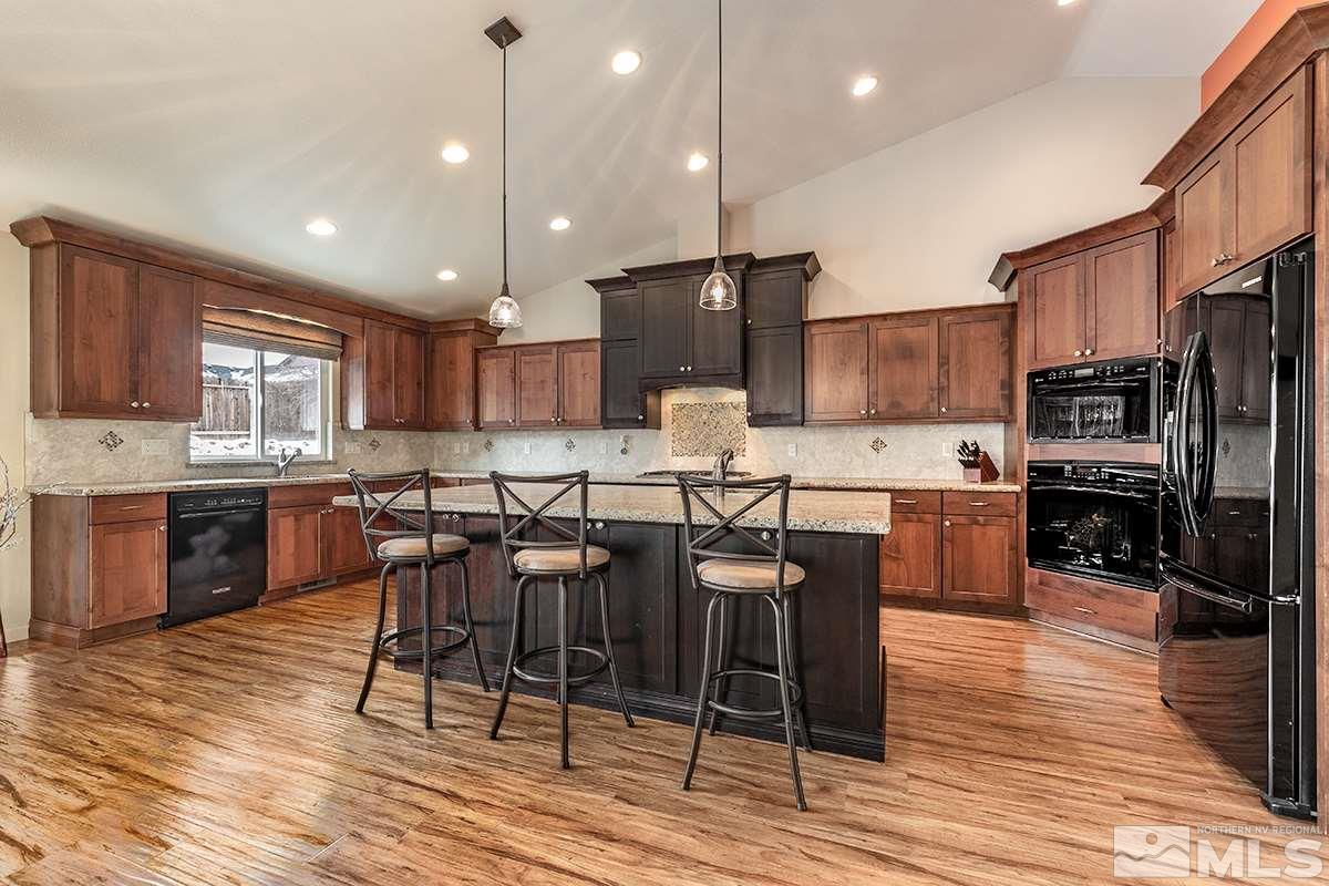 734 Gold River Court Reno, NV 89521 - Photo 6 of 21 a kitchen with stainless steel appliances kitchen island granite countertop a refrigerator a stove a sink a dining table and chairs with wooden floor