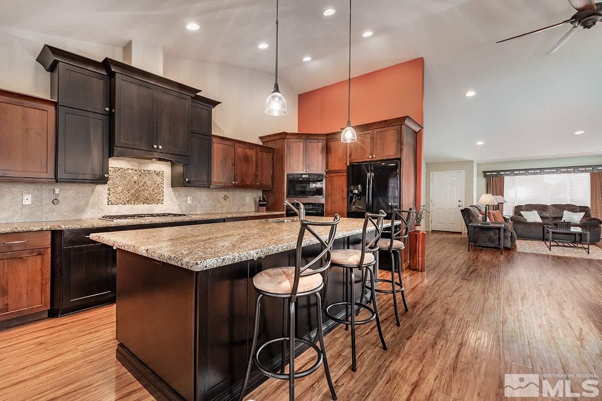 734 Gold River Court Reno, NV 89521 - Photo 8 of 21 a kitchen with granite countertop a table chairs stove a refrigerator and cabinets