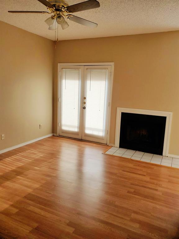 a view of an empty room with a fireplace and a ceiling fan