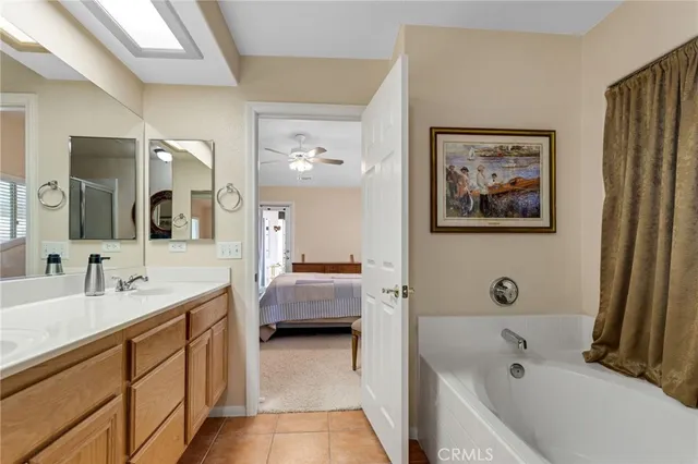 a en suite spacious bathroom with a tub double vanity and view bedroom