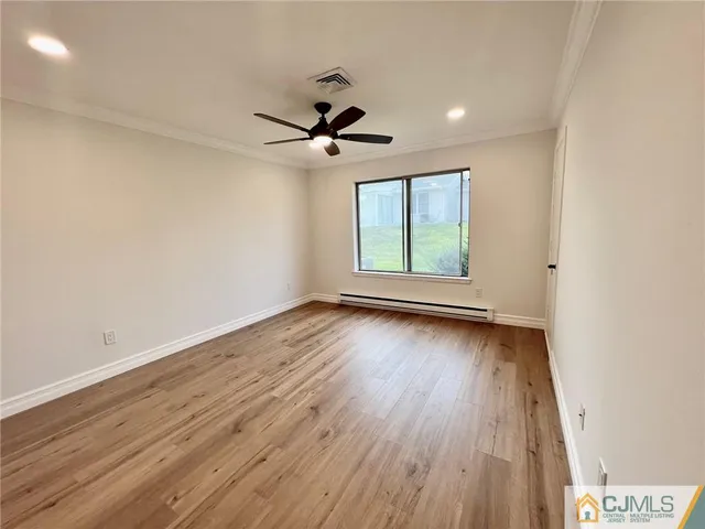 an empty room with wooden floor ceiling fan and windows