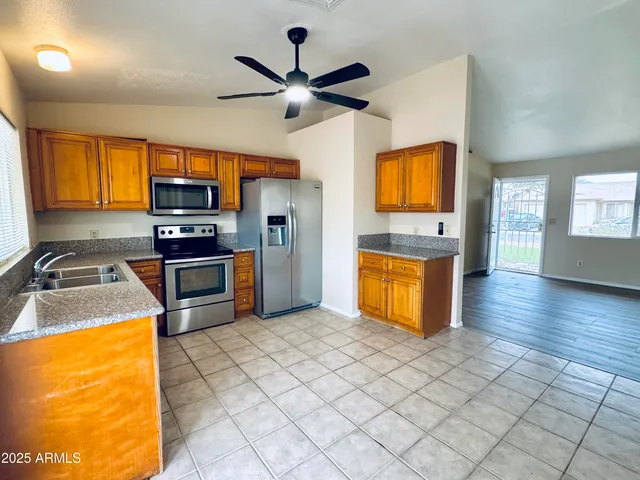 a kitchen with stainless steel appliances granite countertop a stove top oven a sink dishwasher and a refrigerator with wooden floor