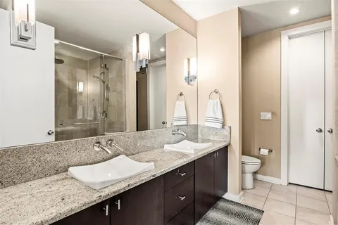 a bathroom with a granite countertop double vanity sink and a mirror