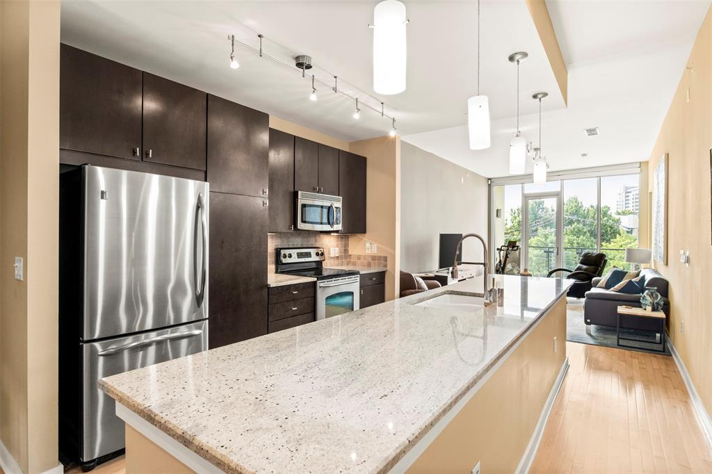 2950 McKinney Avenue, Unit 412 Dallas, TX 75204 - Photo 8 of 26 a kitchen with stainless steel appliances granite countertop a refrigerator a sink dishwasher a stove and a dining table with wooden floor