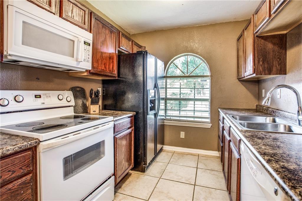 6817 Haltom Road Fort Worth, TX 76137 - Photo 18 of 25 Kitchen featuring wood cabinetry, speckled countertops, white appliances, and a double basin stainless steel sink