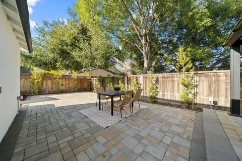 a view of a patio with table and chairs and couches with wooden fence and plants