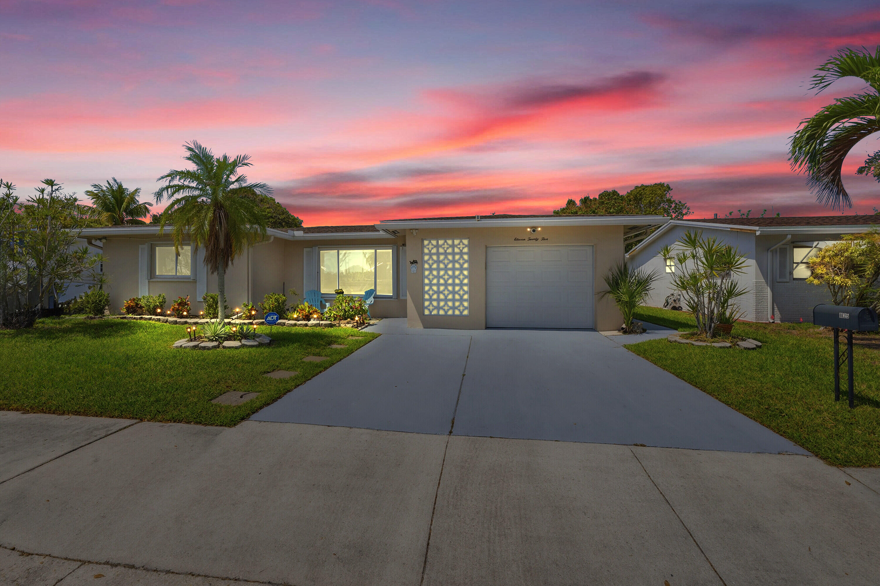 a front view of a house with a yard and potted plants