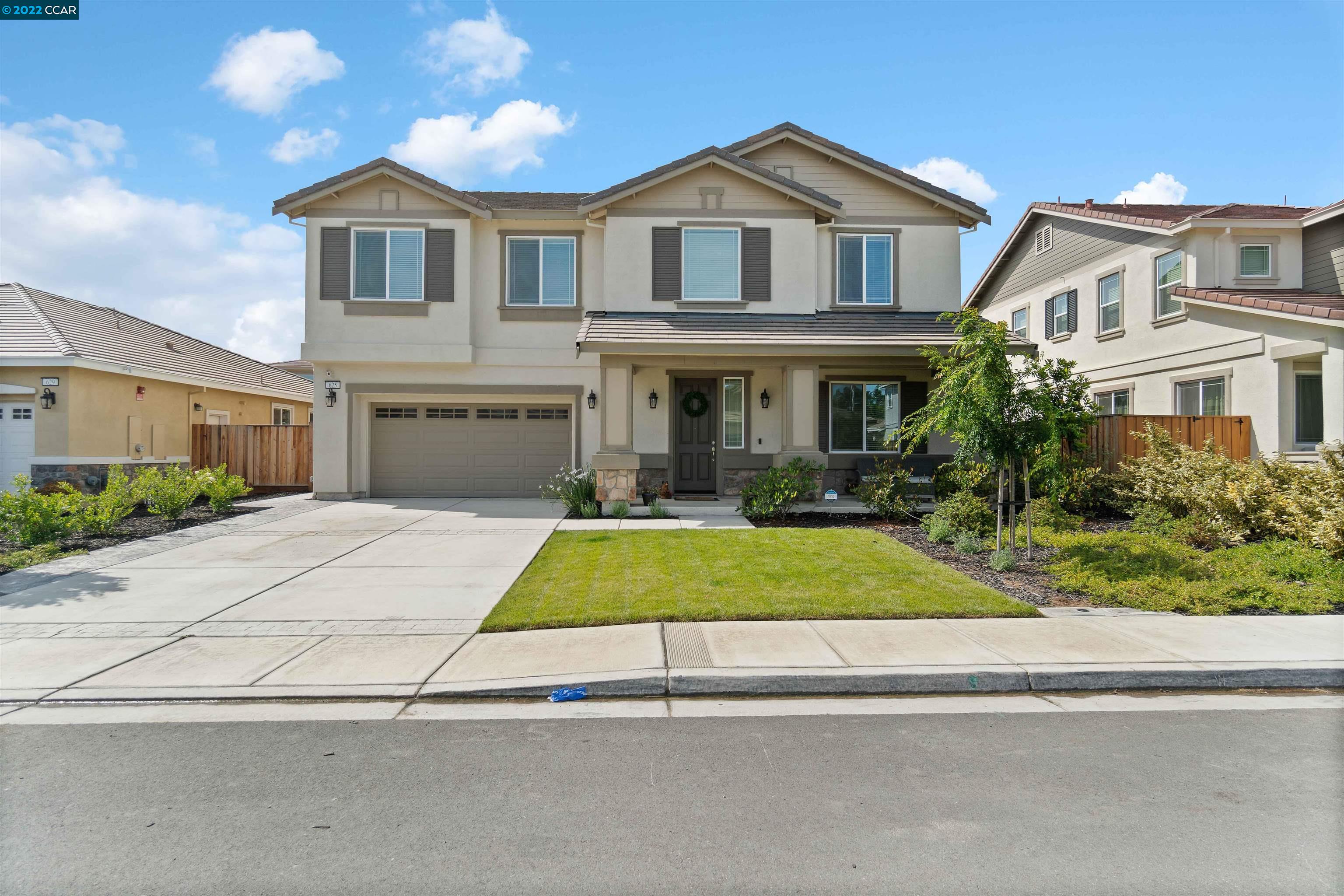 a front view of a house with garage and plants