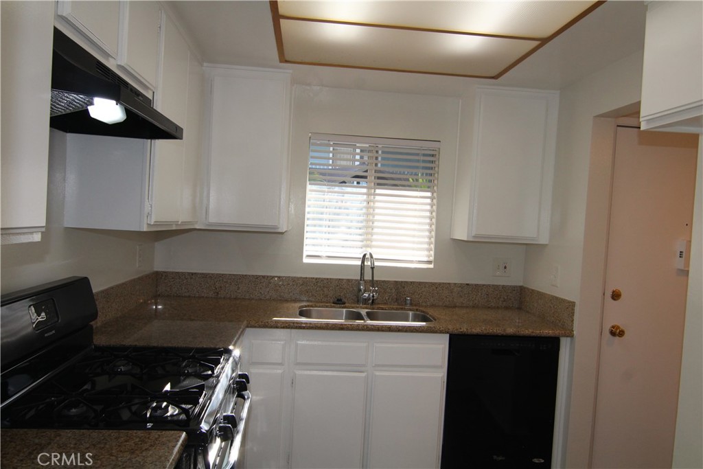 955 East 3rd Street, Unit 204 Long Beach, CA 90802 - Photo 6 of 37 a kitchen with granite countertop a sink a stove and cabinets
