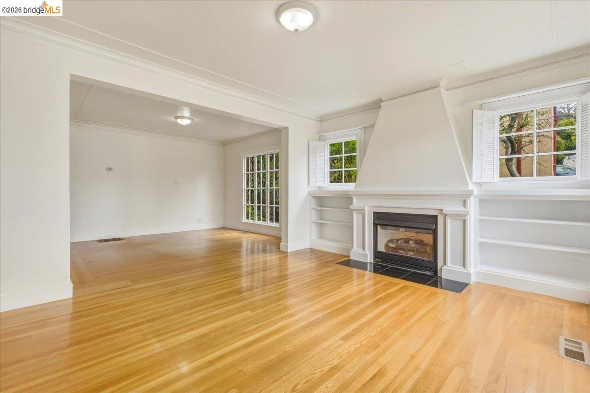2403 Cedar Street Berkeley, CA 94708 - Photo 20 of 33 Living room featuring wood-finish flooring, a fireplace with a black tile hearth, and built-in shelving