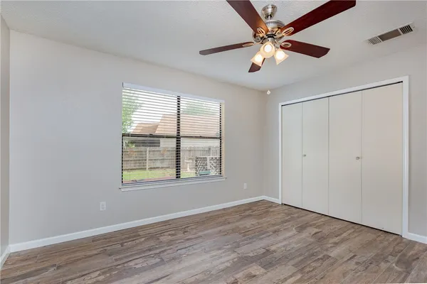 a view of an empty room with window and a ceiling fan