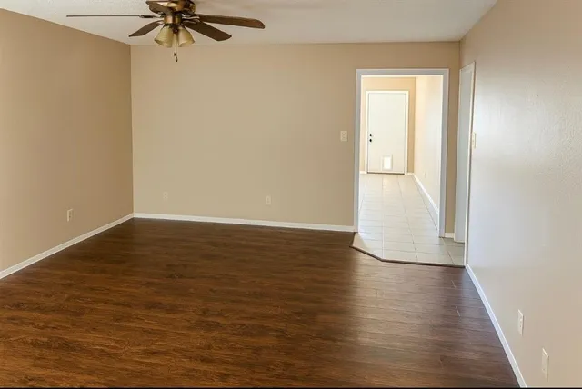 a view of a room with wooden floor and a ceiling fan