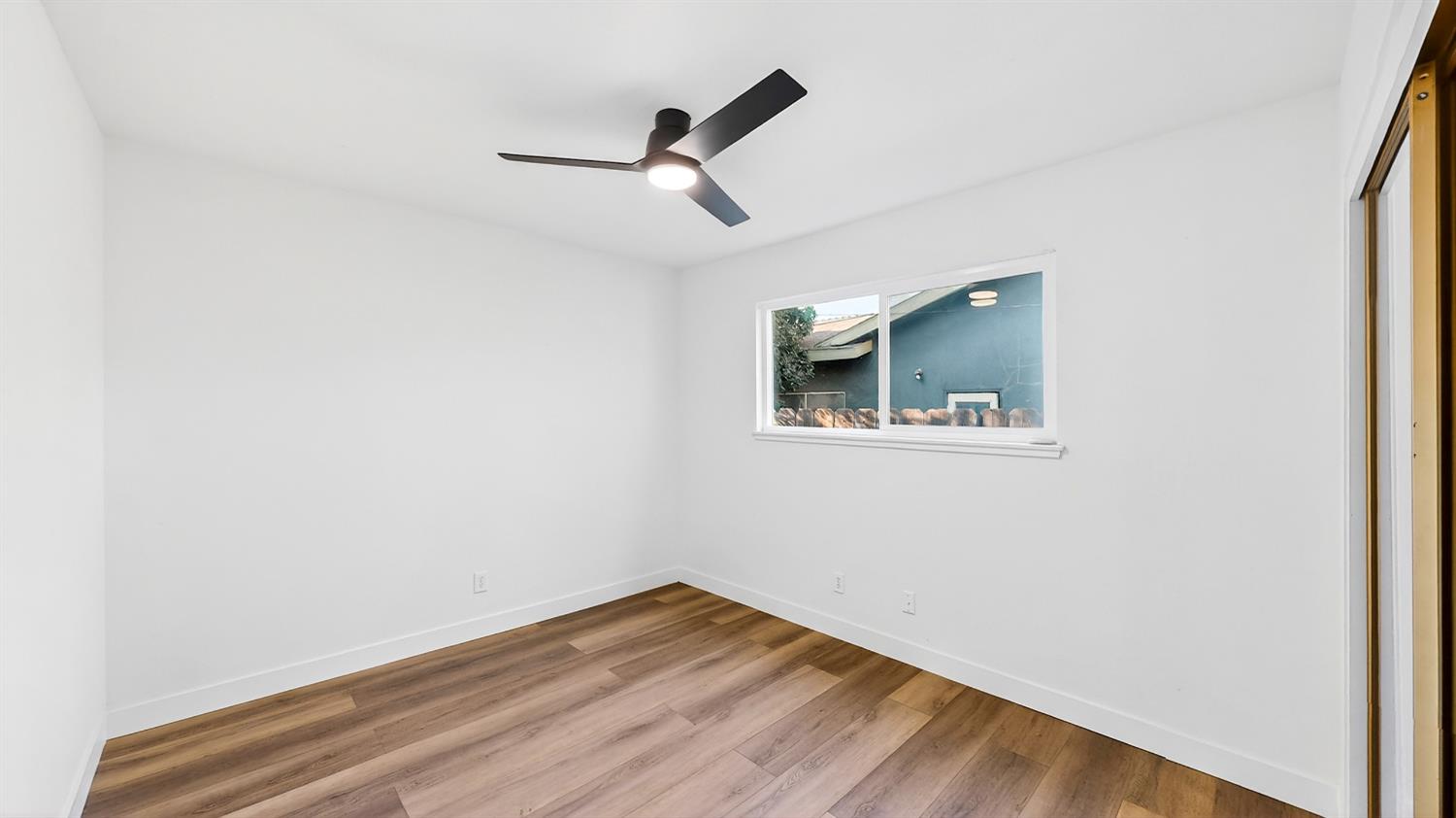 1611 East Olive Avenue Merced, CA 95340 - Photo 22 of 43 an empty room with wooden floor ceiling fan and window