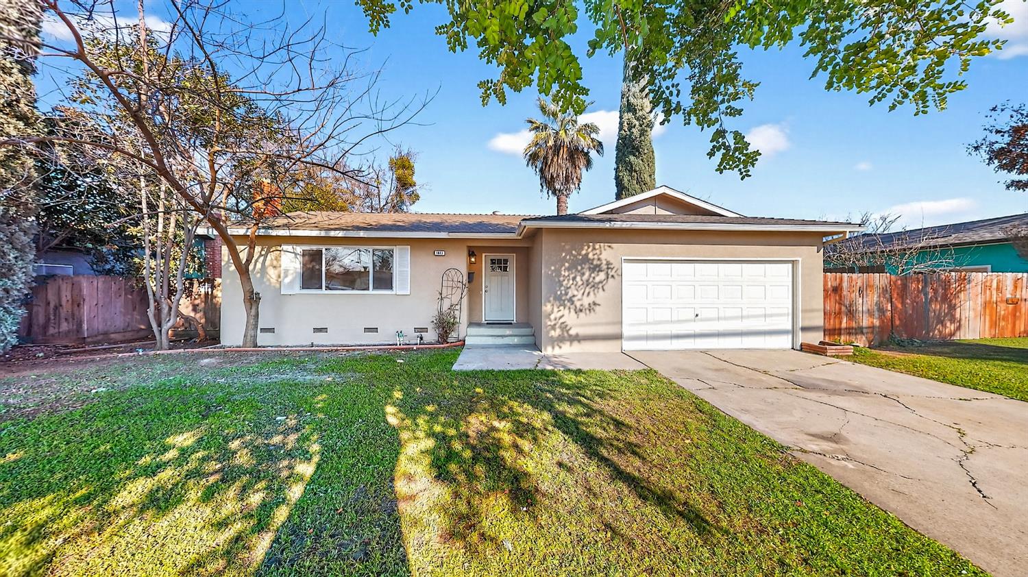 1611 East Olive Avenue Merced, CA 95340 - Photo 4 of 43 a front view of a house with a garden and trees