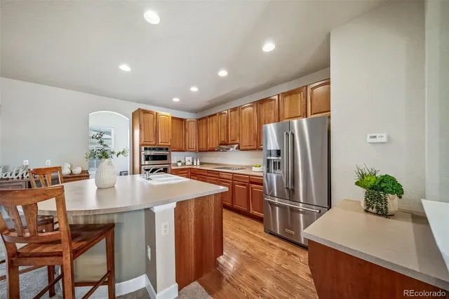 a kitchen with stainless steel appliances granite countertop a refrigerator a sink a stove a dining table and chairs