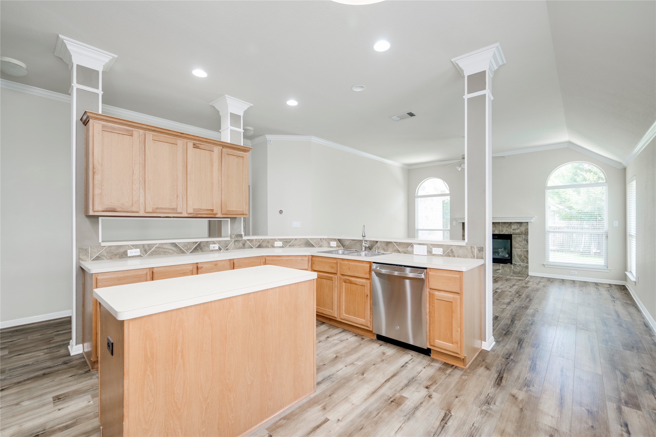 1813 Nelson Ranch Loop Cedar Park, TX 78613 - Photo 10 of 39 A contemporary kitchen with light wood cabinetry and an island overlooks a spacious living area with vaulted ceilings and a fireplace.